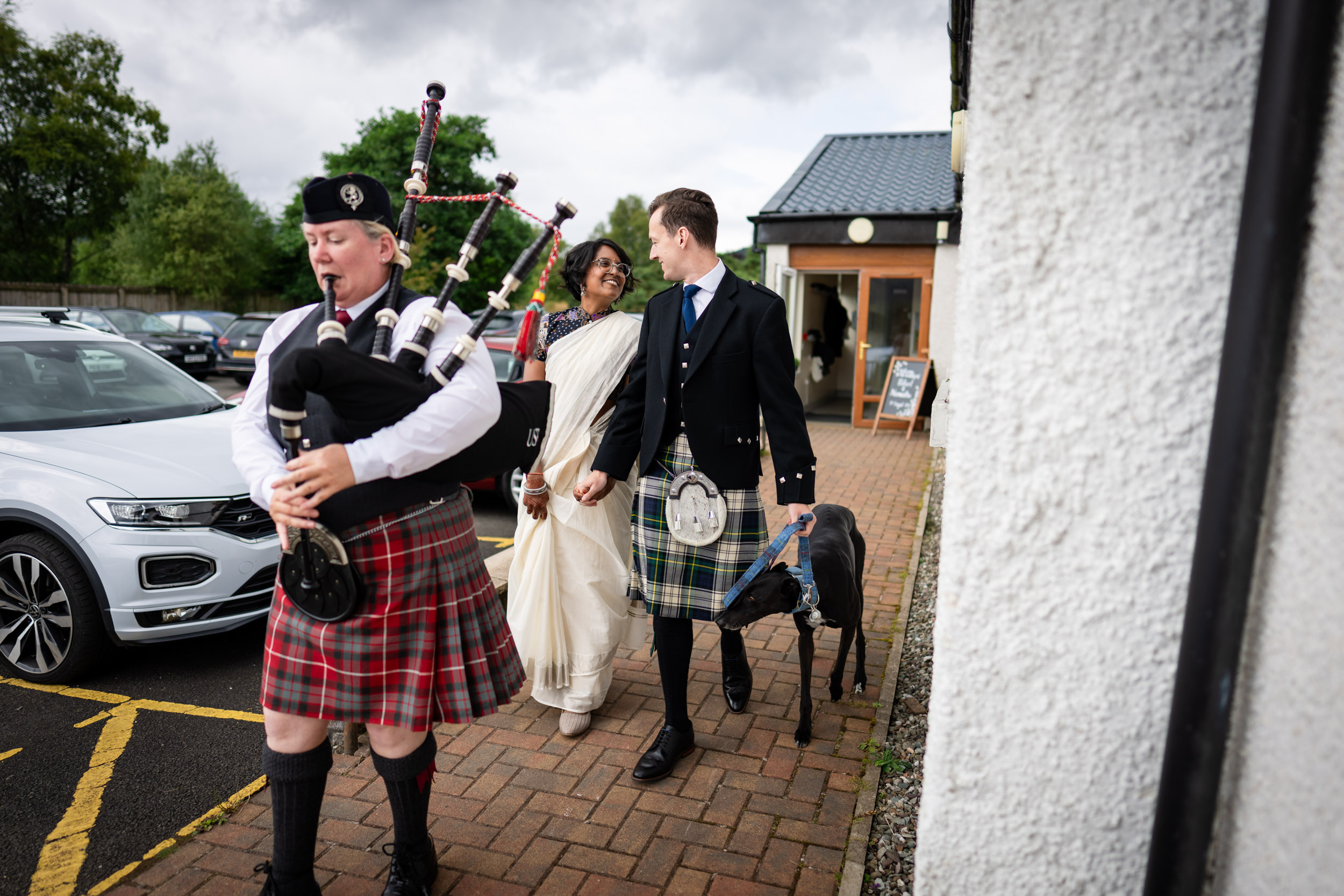 couple arrive with piper and dog Scottish Indian Kinlochard wedding